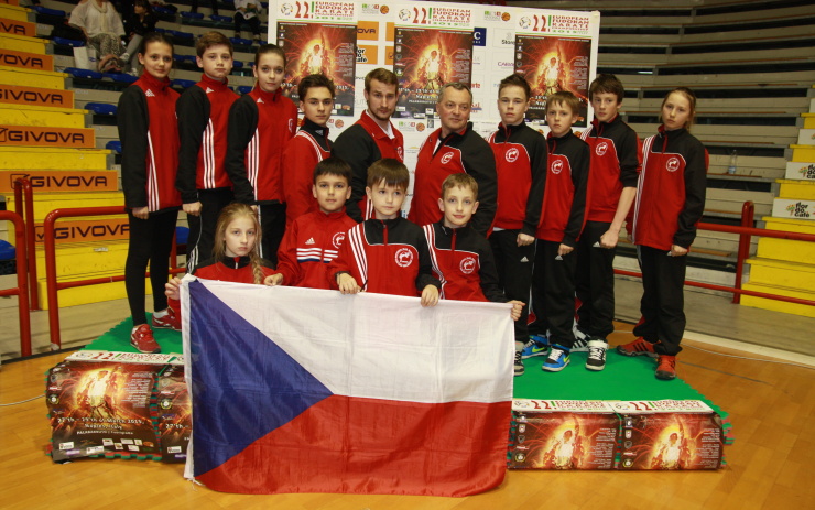 Výprava s trenéry uprostřed na stupních vítězů z desek tatami. Foto: Hana Husáková
