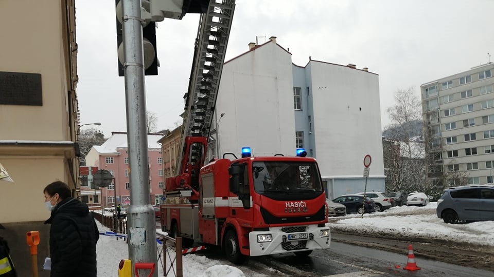 Hasiči odklízejí sníh ze střechy budovy soudu. Strážníci řídí dopravu